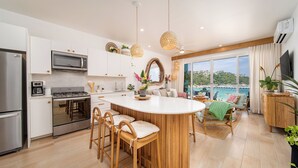 Una cocina moderna con una isla central, electrodomésticos de acero inoxidable y vistas al mar.