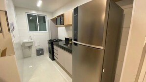 A modern kitchen with stainless steel appliances, a built-in oven, and a microwave. - Edifício Promenade II - Apto 403 (Maceio)