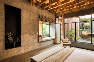 Une chambre moderne avec un grand lit, une fenêtre donnant sur un paysage verdoyant et un banc intégré.