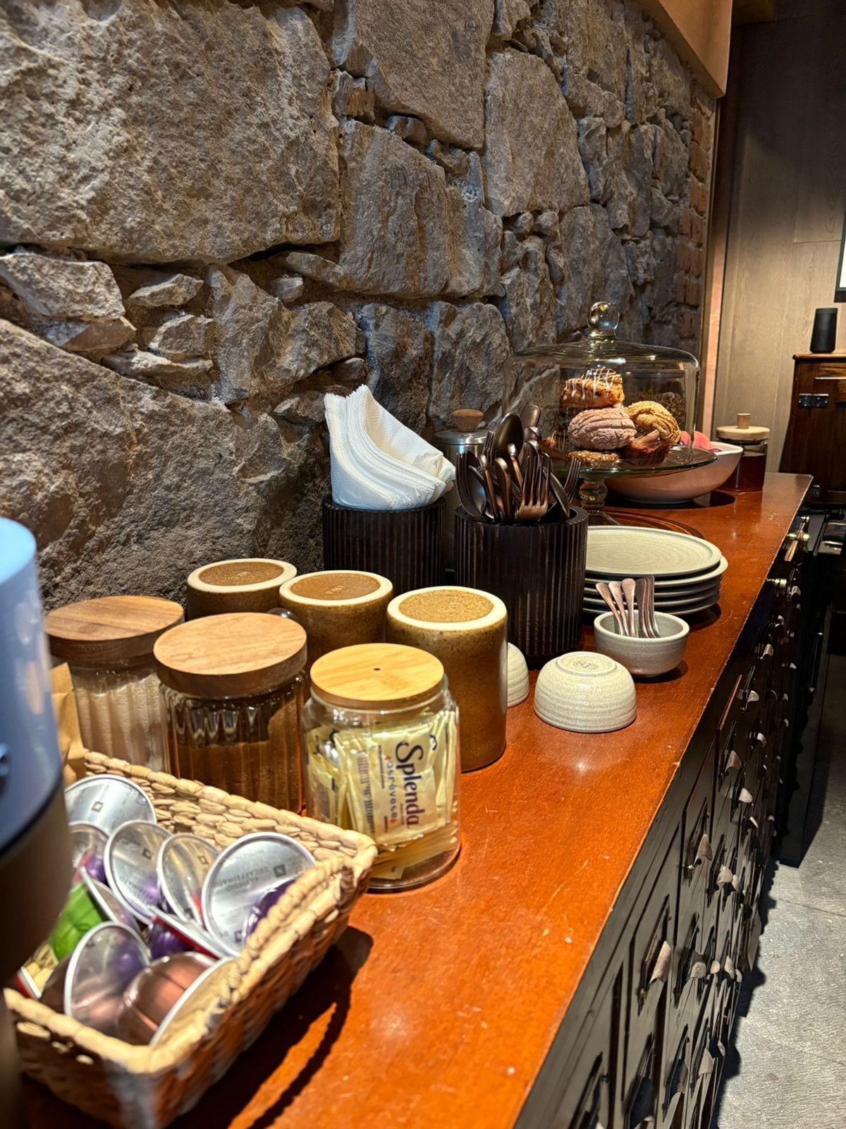 Un buffet de petit-déjeuner proposant une variété d’aliments, d’ustensiles et de récipients, le tout disposé sur un comptoir en bois.