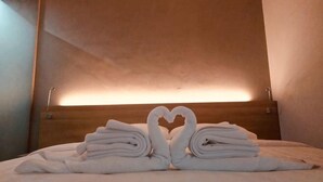 A hotel room with a bed, a heart-shaped towel arrangement, and a wooden headboard. - Hotel Marina Airport (West Semarang)