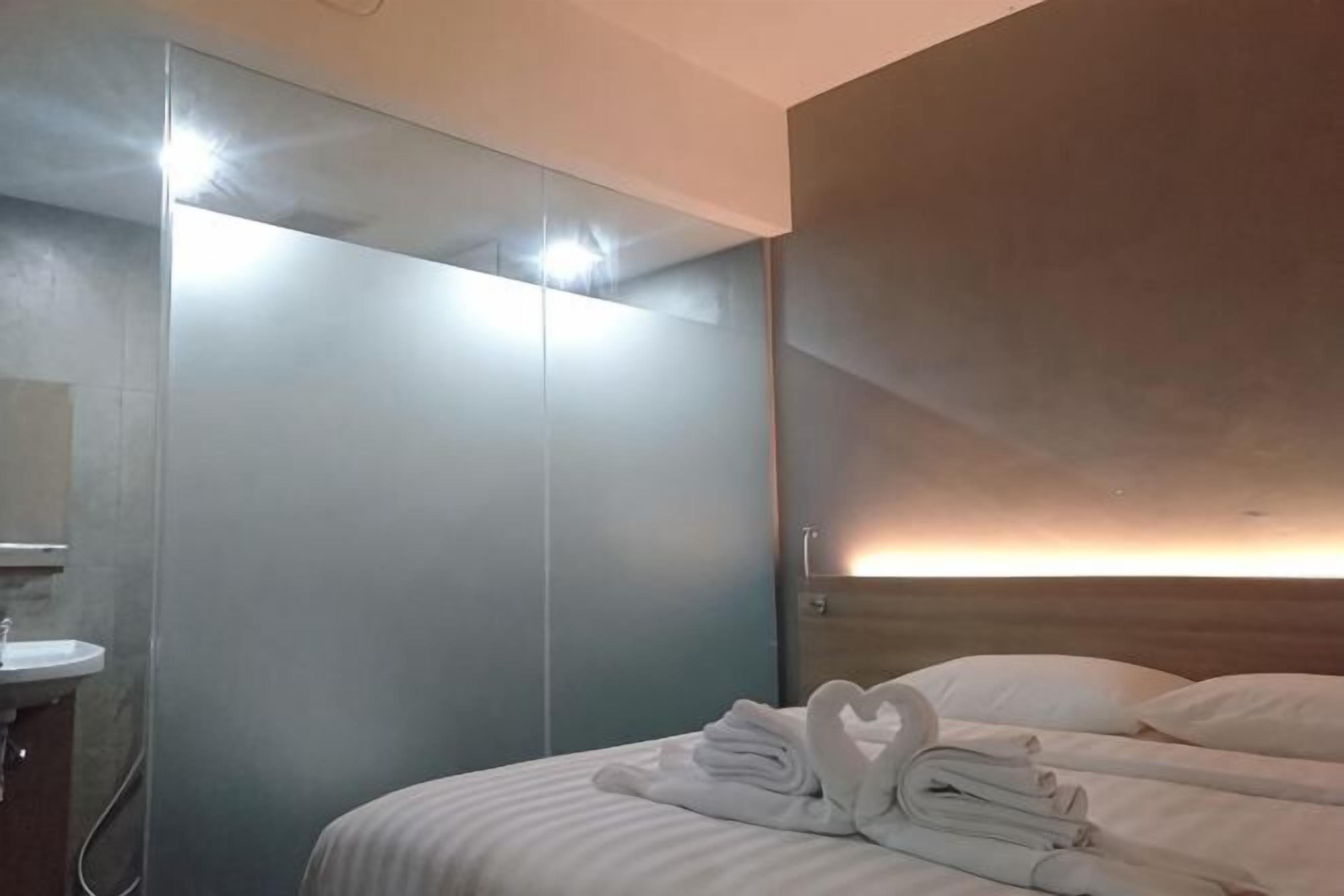 A hotel room with a bed, a mirror, a sink, and a wardrobe.