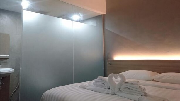 A hotel room with a bed, a mirror, a sink, and a wardrobe. - Hotel Marina Airport (West Semarang)