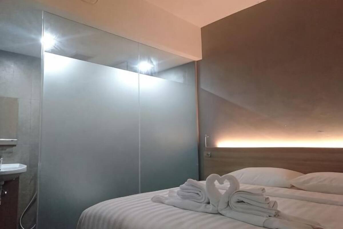A hotel room with a bed, a mirror, a sink, and a wardrobe.