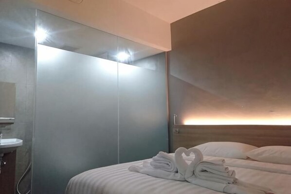 A hotel room with a bed, a mirror, a sink, and a wardrobe.