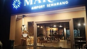 The exterior of Marina Airport Semarang with a prominent sign and a glass entrance. - Hotel Marina Airport (West Semarang)