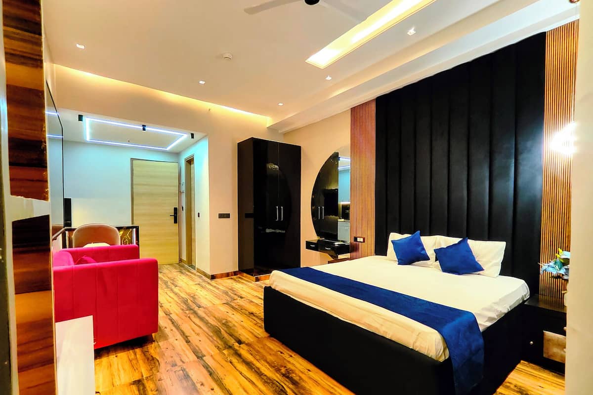 Una habitación de hotel moderna con una cama grande, un sillón rojo y suelo de madera.