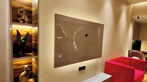 Un salon moderne doté d’un grand téléviseur à écran plat fixé au mur, d’un parquet et d’un canapé rouge.