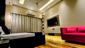 Un salon moderne avec un plancher en bois, un canapé rouge, un téléviseur à écran plat fixé au mur et un ventilateur de plafond.