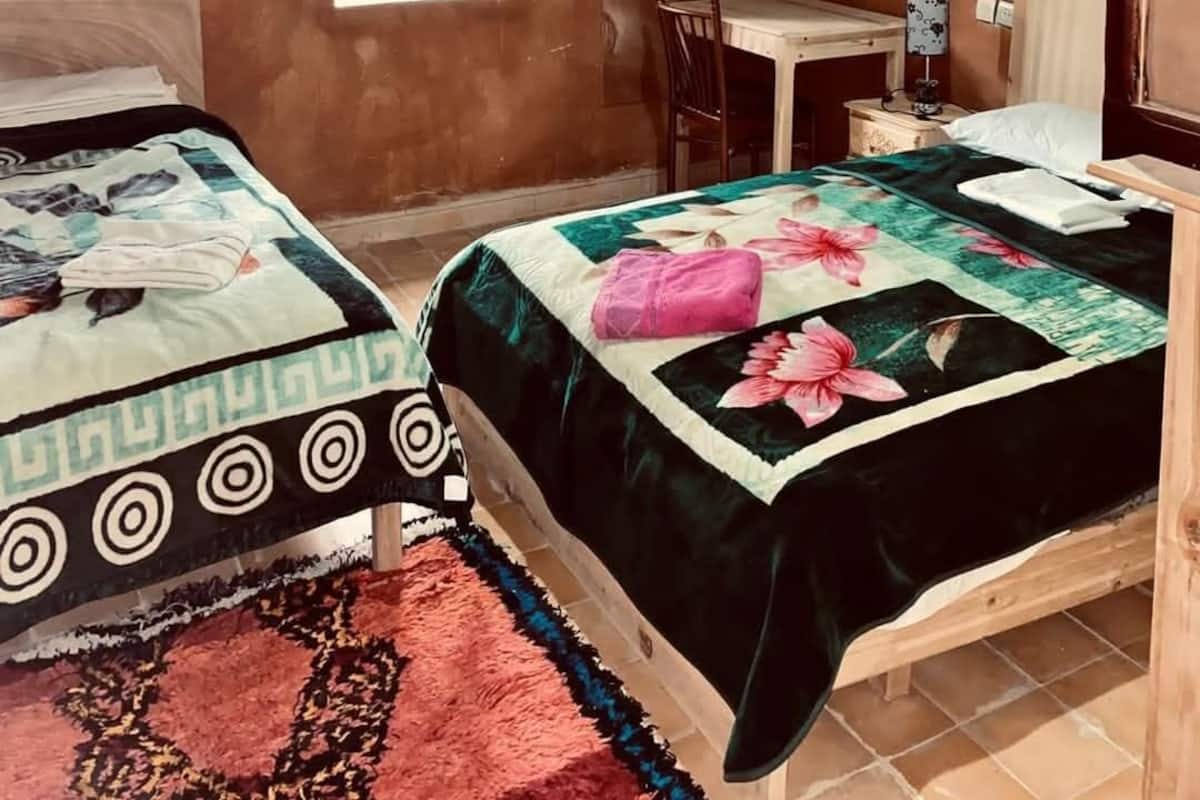 Une chambre avec deux lits, une petite table et une chaise.