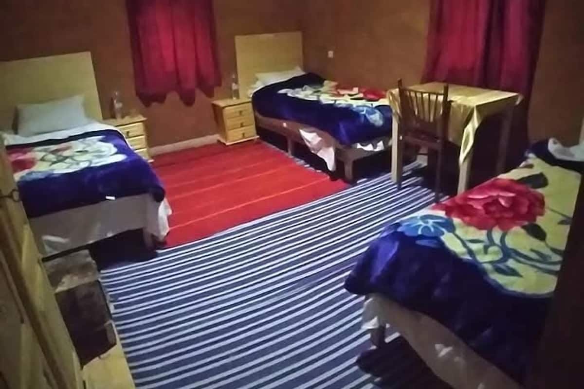 Une chambre avec deux lits, une petite table et une chaise.