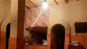 A rustic interior with wooden beams, a wooden reception desk, and a tiled floor. - Hôtel-Kasbah Aberdouz (Ait Yahya)