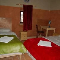 Habitación con dos camas, un escritorio, una silla y una ventana con cortina.