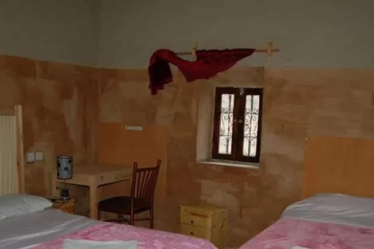 Une chambre avec deux lits, un bureau, une chaise et une fenêtre.