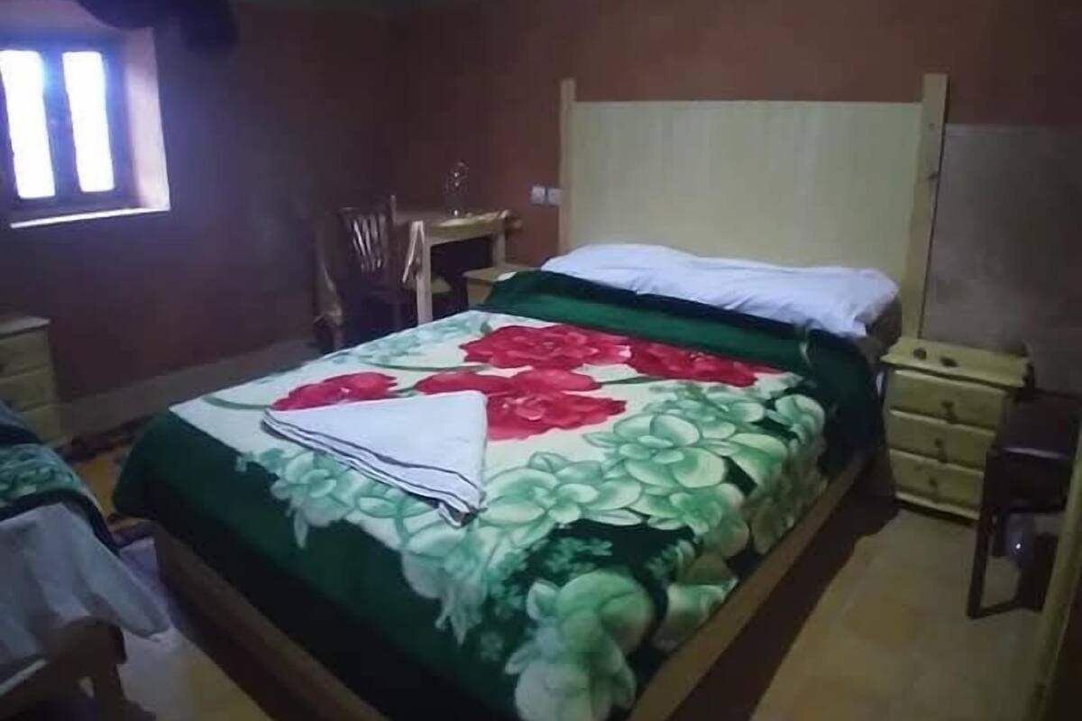 Une chambre à coucher comprenant un lit, une table de chevet, une chaise, un bureau et une fenêtre.