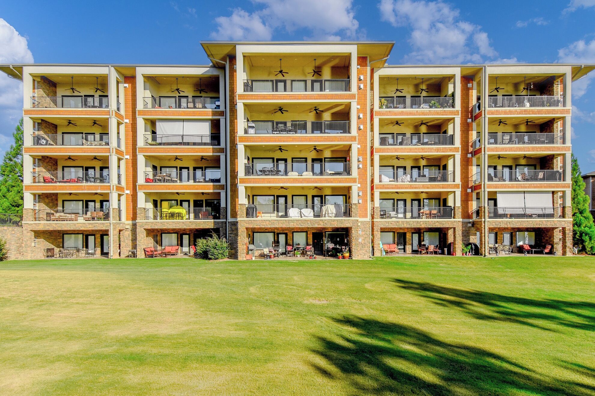 A multi-story hotel with balconies, outdoor seating, and a well-maintained lawn.