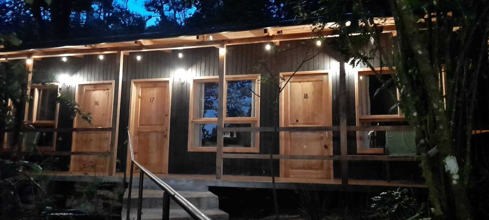 A row of wooden cabins with numbered doors, each with a window and a small porch area.
