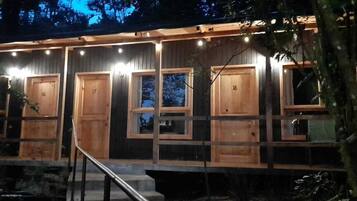 Eine Reihe aus Holzbungalows mit nummerierten Türen, jedes mit einem Fenster und einer kleinen Veranda.