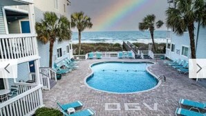 Área da piscina com espreguiçadeiras, piscina e vista para o oceano.