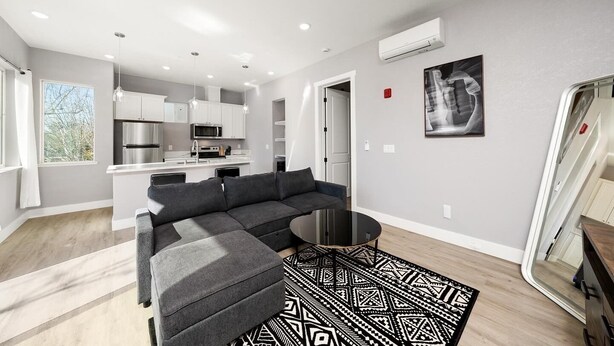 A modern apartment with a grey sofa, a black coffee table, and a patterned rug.
