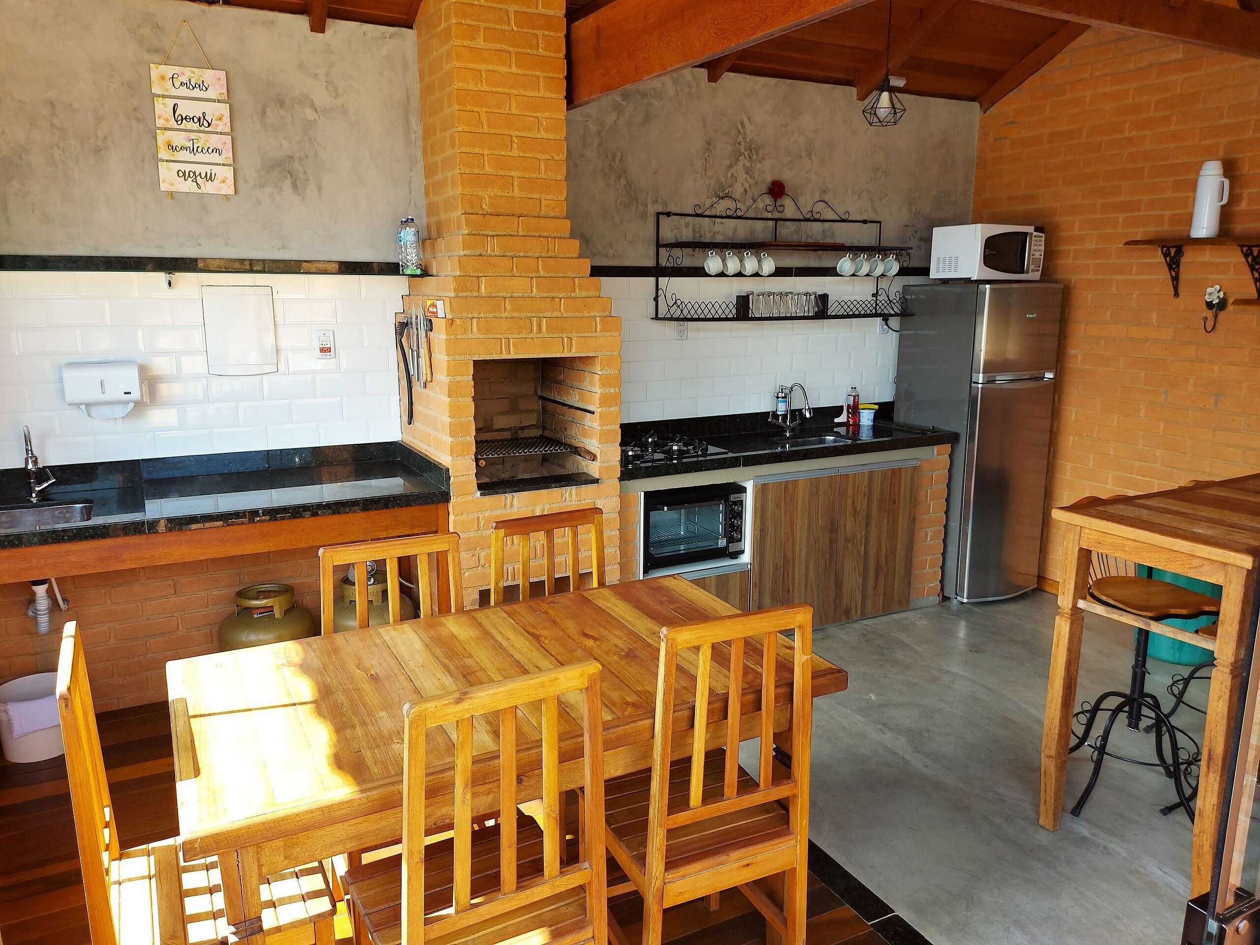 A kitchen with a brick oven, a microwave, a refrigerator, and wooden furniture.