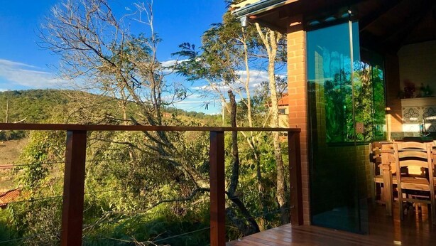 A wooden deck with a glass balustrade overlooking a lush landscape with trees and hills. - Villa da Serra Ibitipoca (Lima Duarte)