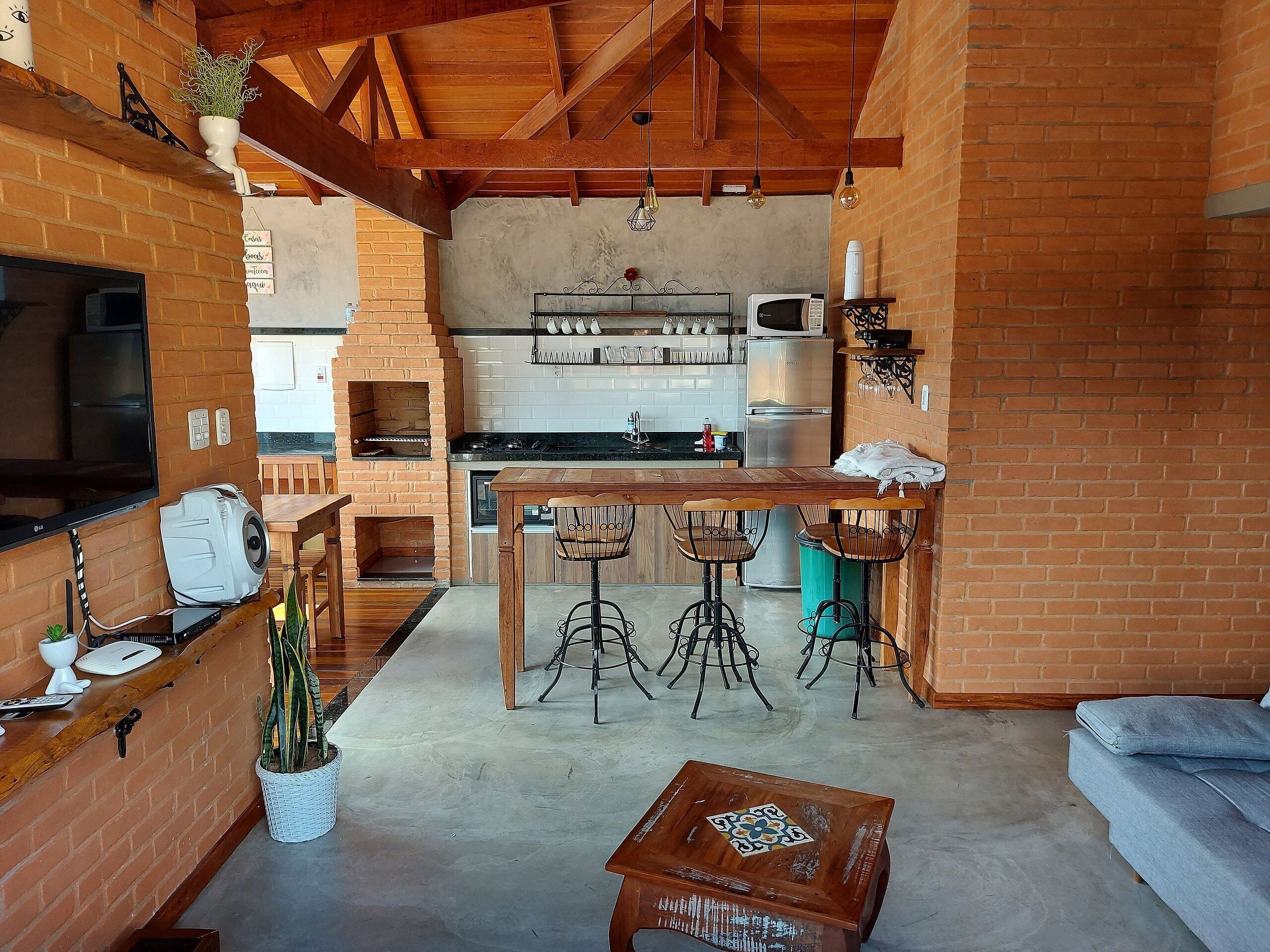 A cozy kitchen with a brick oven, wooden bar stools, and a dining table.