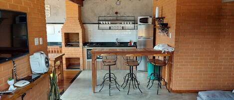 A cozy kitchen with a brick oven, wooden bar stools, and a dining table.