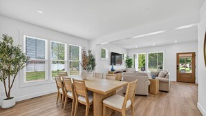 A spacious living area with a wooden dining table, comfortable seating, and large windows offering views of the outdoors. - NEW BUILD - Walk to Notre Dame, Eddy Street Trader Joes only a half mile away (South Bend)
