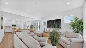 A modern living room with a beige sofa, a coffee table, and a dining area with a wooden table and chairs. - NEW BUILD - Walk to Notre Dame, Eddy Street Trader Joes only a half mile away (South Bend)