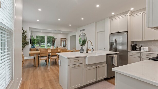 A modern kitchen with white cabinetry, a stainless steel refrigerator, and a dining area with wooden furniture. - NEW BUILD - Walk to Notre Dame, Eddy Street Trader Joes only a half mile away (South Bend)