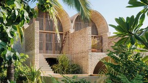 Ein modernes Haus mit Backsteinfassade, großen Fenstern und einer überdachten Außenbereich mit Pflanzen.