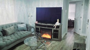 A living room with a sofa, a glass coffee table, a fireplace, and a television.