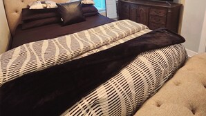 A bedroom with a bed, a dresser, a TV, and a ceiling fan.
