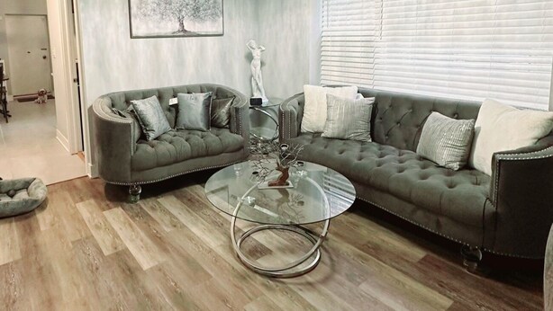 A living room with a sectional sofa, a glass coffee table, and a chandelier.