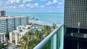 A high-rise building with a view of the ocean and palm trees. - RN STUDIO - APTO 903 (Maceio)