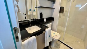 A modern bathroom with a glass-enclosed shower, a white sink, and a black countertop. - RN STUDIO - APTO 903 (Maceio)