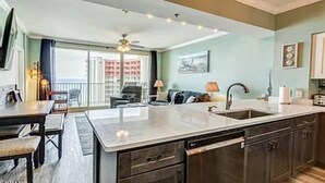 A modern kitchen with a central island, dark cabinetry, and a view to a balcony.