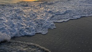 A beach with waves and a sunset.