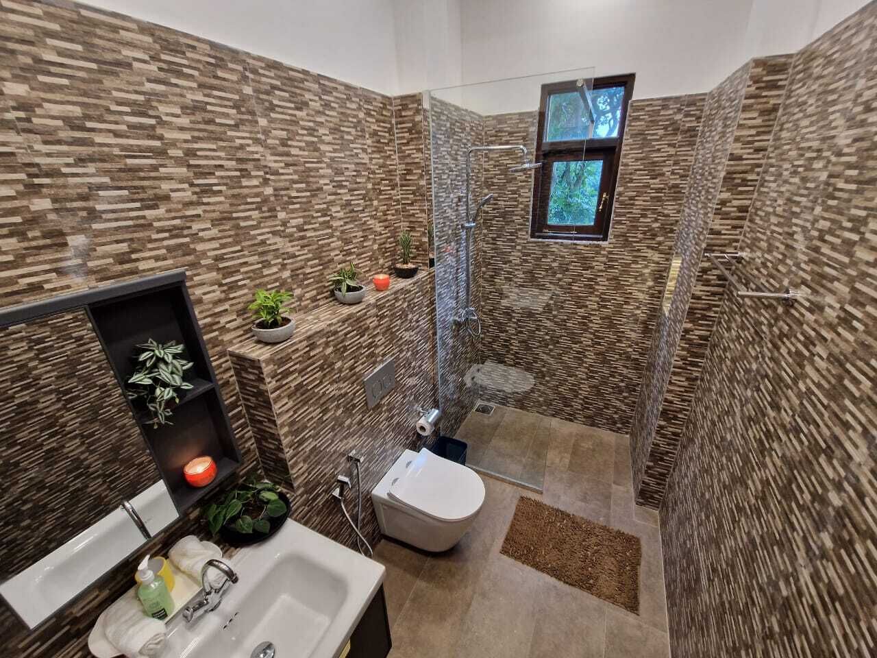 A modern bathroom with a stone wall design, a glass shower enclosure, and a small window.