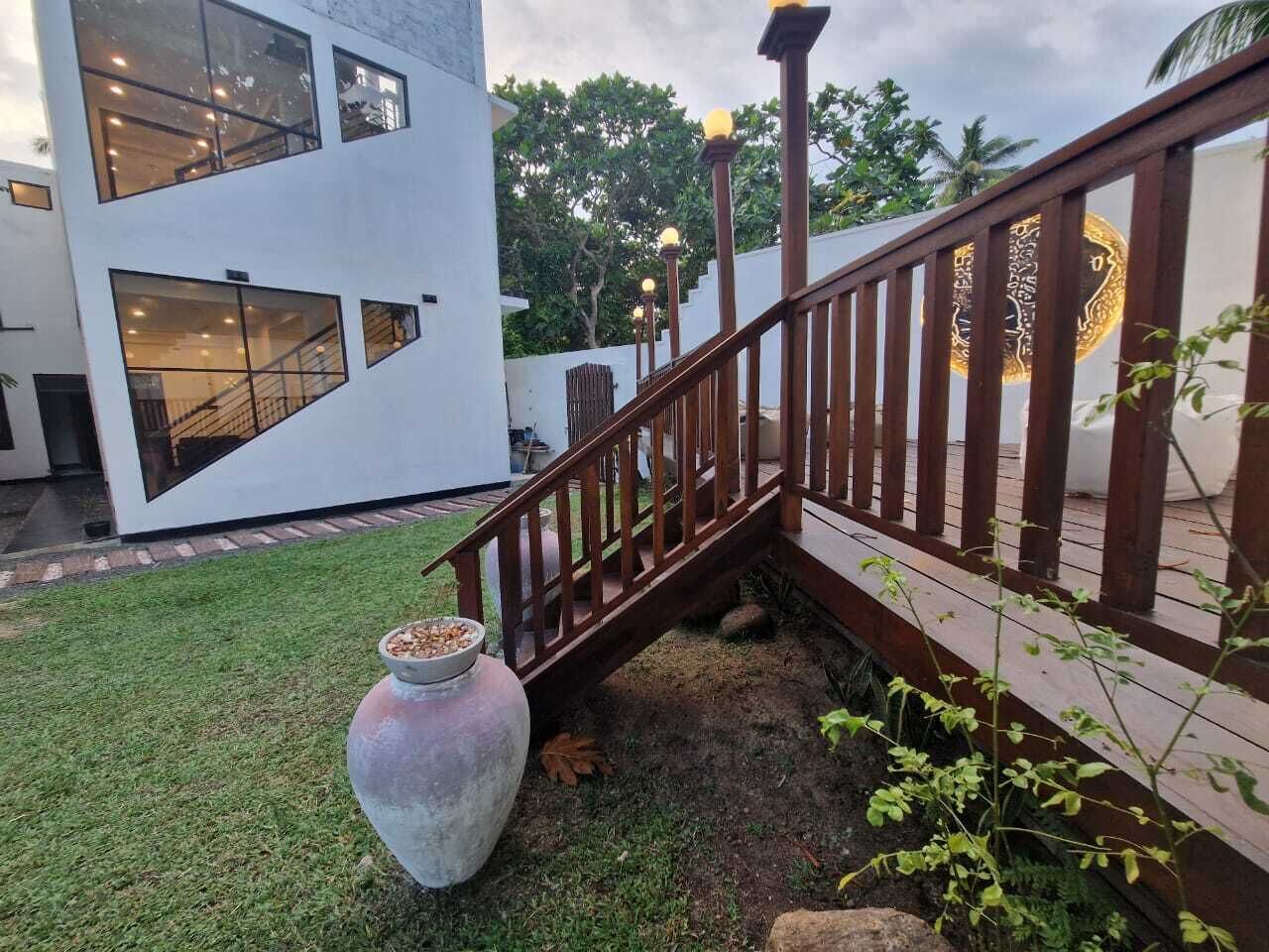 A modern building with large windows, a wooden staircase, and a grassy area with a large pot.