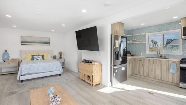 Une chambre à coucher moderne avec un lit, une table de chevet et un téléviseur fixé au mur.