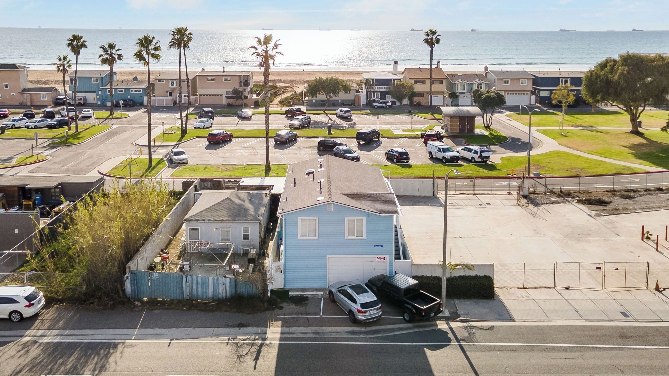 Un quartier résidentiel situé sur la côte, avec un parking, des maisons et une vue sur l’océan.