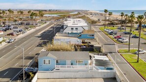 Une route côtière bordée d’une rangée de maisons bleues, une plage et des palmiers.