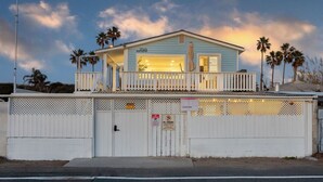 A two-story building with a balcony, a sign indicating '17165 Pacific Coast Hwy,' and a gated entrance. - Walk to the Sand! Ocean Views, Balcony & Parking Sunset Surf (Huntington Beach)