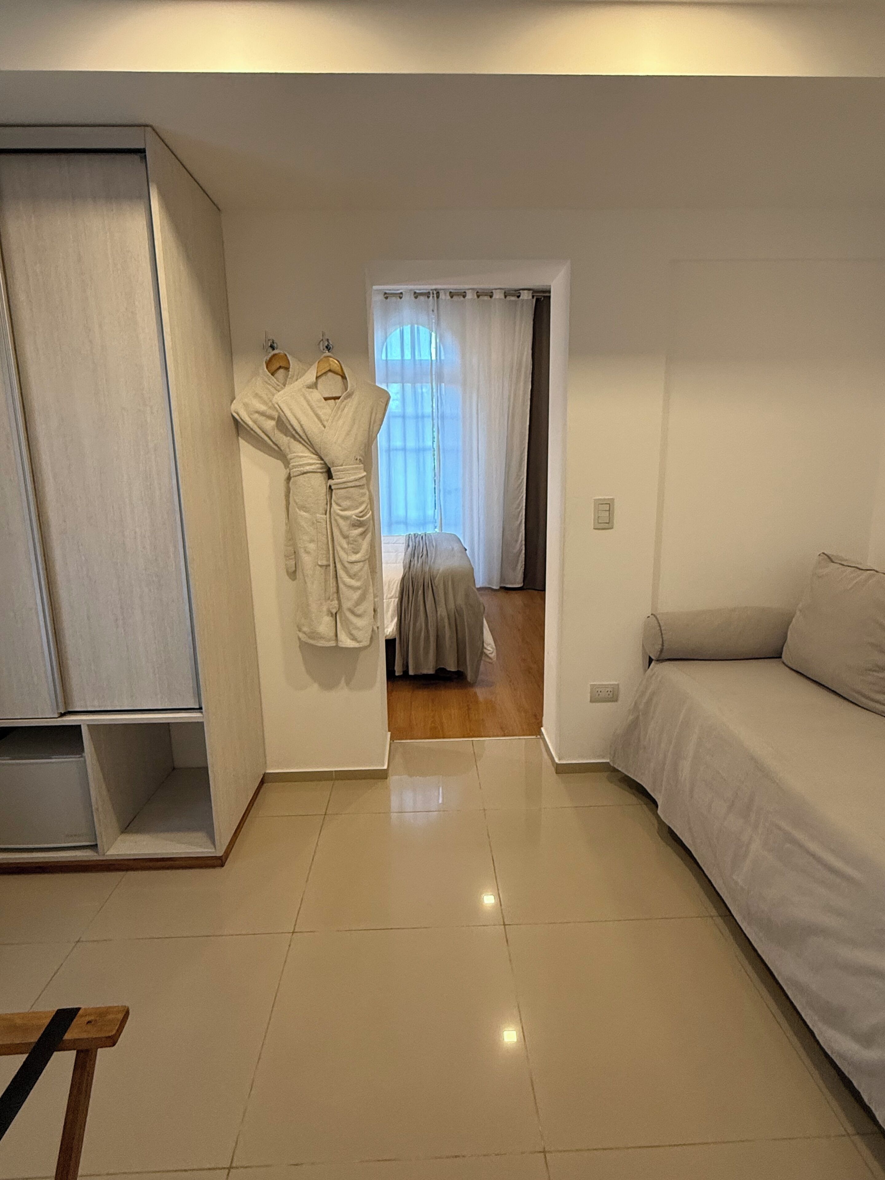 Un dormitorio moderno con un armario grande, una cama con edredón gris y suelo de madera.