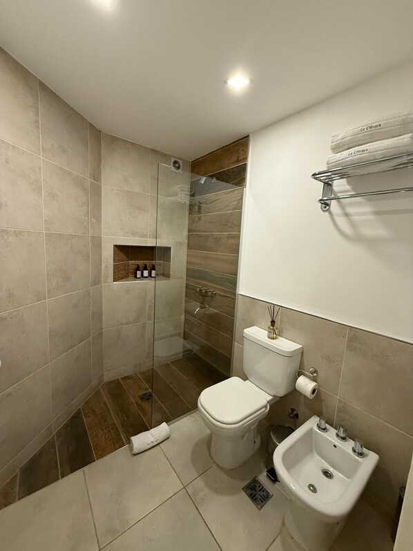 A modern bathroom with a shower, toilet, bidet, and a towel rack.