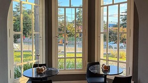 A dining area with a view of a garden and street through large arched windows. - La Olivia Hotel Boutique & Spa (La Falda)