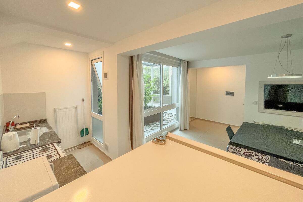 A modern kitchen with a built-in oven, a sink, and a window with curtains.