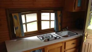 A compact kitchen with wooden cabinets, a built-in dishwasher, a gas stove, and a sink. - La roulotte du petit bois (Thénouville)